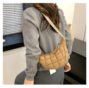 Close-up of beige quilted crossbody bag showing soft puff texture and woven zipper detail