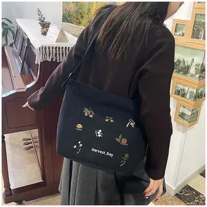 Detail of embroidered corduroy tote bag showing floral patterns and Harvest Day text