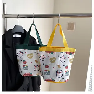 Detail of cute canvas bucket bags with cartoon rabbit prints in yellow and green colors