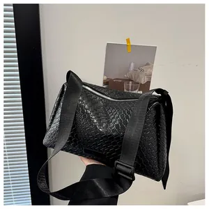 Détail du sac tressé noir avec fermeture éclair argentée et large bandoulière en nylon