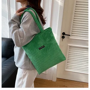 Dettaglio della borsa tote in velluto a coste verde con righe verticali e patch moda