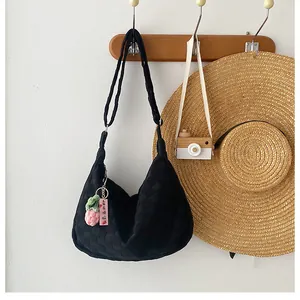 Detail of waffle-textured black shoulder bag with a cute knitted strawberry charm