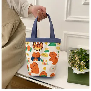 Détail du sac seau en toile blanche avec motif tigre et poignées tissées bleues