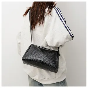 Détail de la texture en cuir tressé noir sur un sac à bandoulière rectangulaire chic