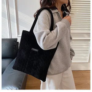 Dettaglio della borsa tote in velluto a coste nero con trama e etichetta fashion