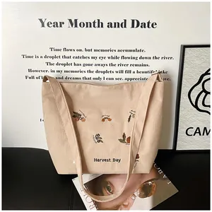 Detailed close-up of beige corduroy tote bag with colorful flower and Harvest Day embroidery