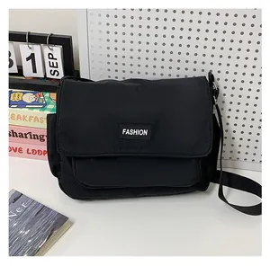 Dettaglio di una borsa a tracolla in tela nera con patch fashion e tracolla regolabile nera