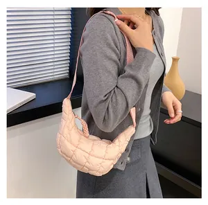 Macro detail of soft light pink quilted fabric and grid texture on a puffy shoulder bag
