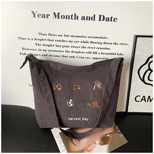 Detailed embroidery of Harvest Day and botanical motifs on brown corduroy tote bag