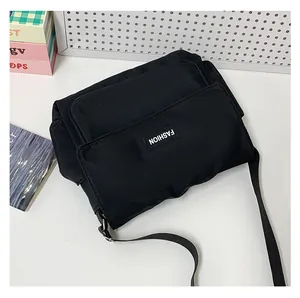 Dettaglio di una borsa messenger in nylon nero con tasca frontale ed etichetta logo