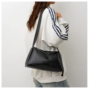 Détail de la texture tressée noire d'un sac à bandoulière minimaliste en cuir pour femme