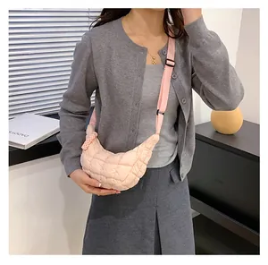 Detailed close-up of light pink quilted nylon crescent bag with adjustable wide strap