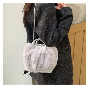 Détail du sac à bandoulière en fausse fourrure grise avec poignée tressée sur modèle