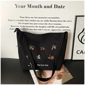 Detailed view of floral embroidery and Harvest Day text on black corduroy tote bag