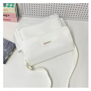 Vista ravvicinata della borsa a tracolla bianca con patta e etichetta su tavolo bianco