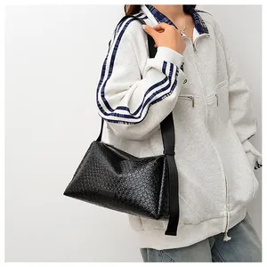 Détails du sac bandoulière tressé noir en cuir texturé avec une large sangle nylon