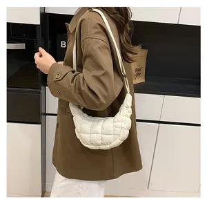 Lifestyle view of a white quilted crescent shoulder bag worn with a casual brown suit blazer