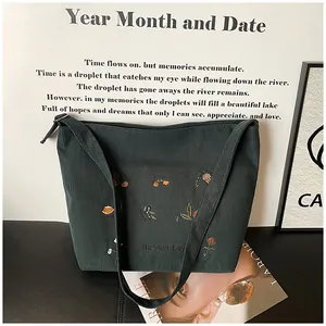 Detailed embroidery of Harvest Day and floral patterns on dark green corduroy tote bag