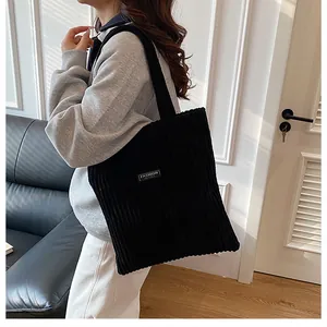 Dettaglio della borsa tote in velluto a coste nero con trama a costine e etichetta