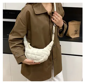 Close-up of white quilted dumpling bag with adjustable strap in a modern kitchen scene