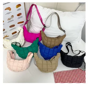 Detailed flat lay of quilted puffy crossbody bags in multiple colors on a soft bed