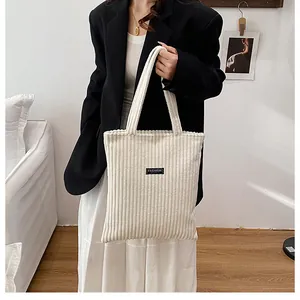 Dettaglio della borsa tote in velluto a coste bianco con texture e etichetta fashion leisure