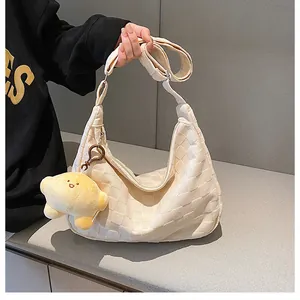 Detail of off-white waffle texture hobo bag with a cute yellow duck plush charm