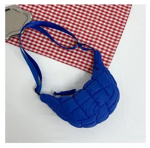 Close-up of bright blue quilted nylon cloud bag on a red and white checkered tablecloth