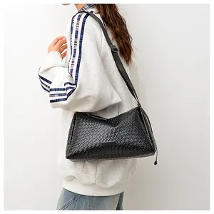 Détail du sac hobo tressé noir avec bandoulière réglable porté par une femme modèle