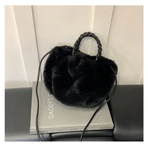 Détail d'un sac nuage en fausse fourrure noire avec poignée en cuir tressé et sangle