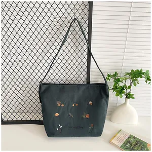 Close-up of dark green corduroy tote bag featuring harvest day floral embroidery