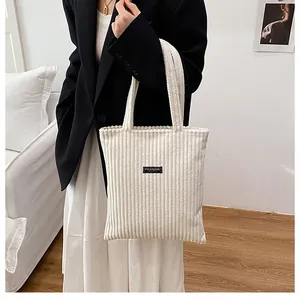 Dettaglio della borsa tote in velluto a coste bianco con trama e etichetta FASHION