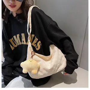 Detail of off-white waffle hobo bag featuring a yellow star plush charm and textured fabric