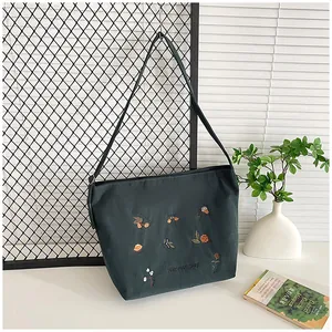 Detail of dark green corduroy tote bag featuring floral harvest day embroidery