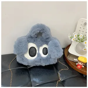 Détail d'un sac en peluche bleu avec broderie de grands yeux et bandoulière dorée