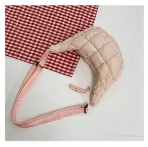 Detailed close-up of pink quilted crescent bag with adjustable strap and zip closure