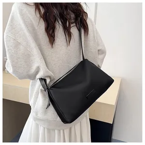 Gros plan du sac bandoulière noir avec fermeture éclair en argent porté sur l'épaule