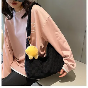 Detail of black waffle texture hobo bag with a cute yellow chick plush pendant charm