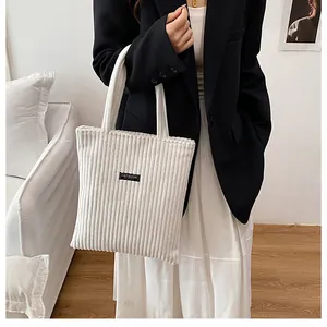 Dettaglio della borsa tote in velluto a coste bianco con etichetta Fashion nera
