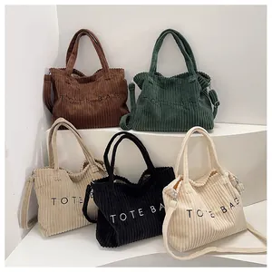 Detail of five corduroy tote bags with letter embroidery in various versatile colors