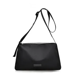 Sac bandoulière noir en nylon tissé avec sangle réglable et plaque métallique élégante