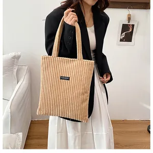 Dettaglio della borsa tote in velluto beige con etichetta fashion e trama a coste