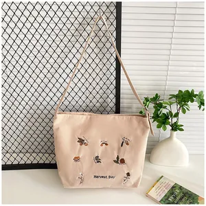 Close-up of beige corduroy tote with harvest acorn embroidery and zip closure detail