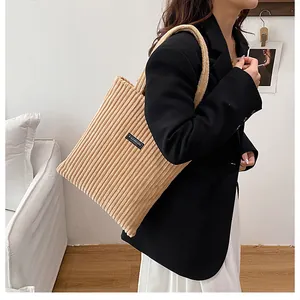 Dettaglio della borsa tote in velluto beige con trama a coste e logo Fashion sulla spalla