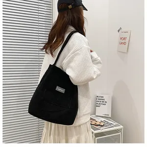 Detail of black corduroy tote bag with vertical stripes and Fashion label on front pocket