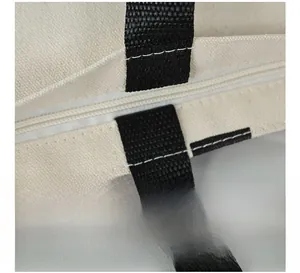 Detailed macro view of reinforced black handle stitching on beige canvas tote bag with zipper