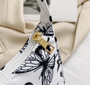 Détail de la fermeture éclair dorée et de l'imprimé papillon sur le sac sous les aisselles