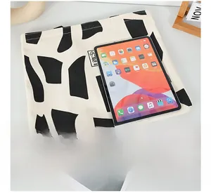 Close-up of cream canvas tote bag with abstract patterns and iPad for size comparison