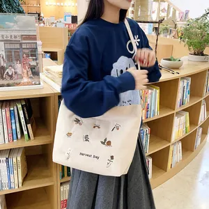 Off-white corduroy tote bag with flower embroidery shown in a cozy bookstore setting