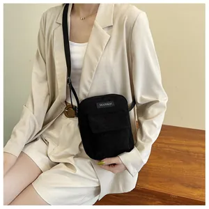 Detailed view of black corduroy crossbody bag worn by model showing texture and strap